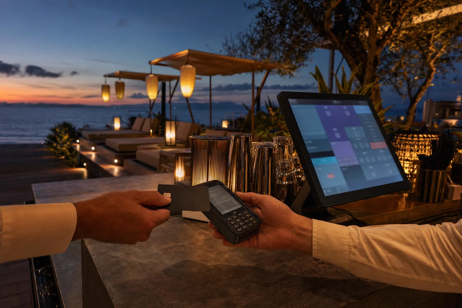 A card payment taken at a beach club bar counter at dusk beside a point-of-sale screen