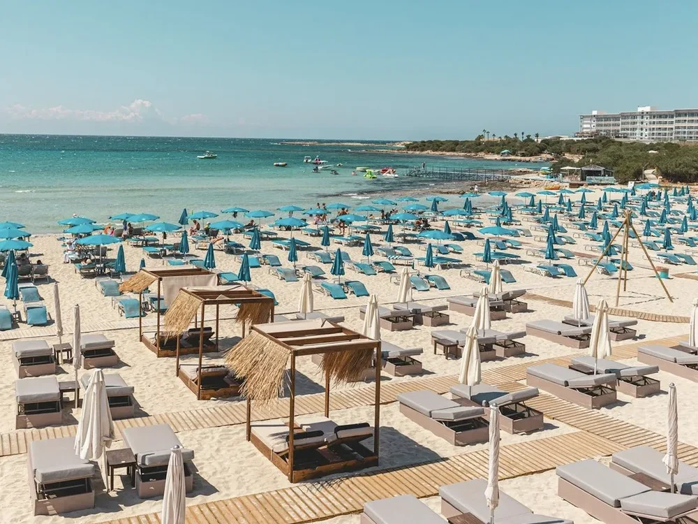 lasmari beach bar on the Cyprus coastline — sunbeds, cabanas and turquoise parasols on white sand