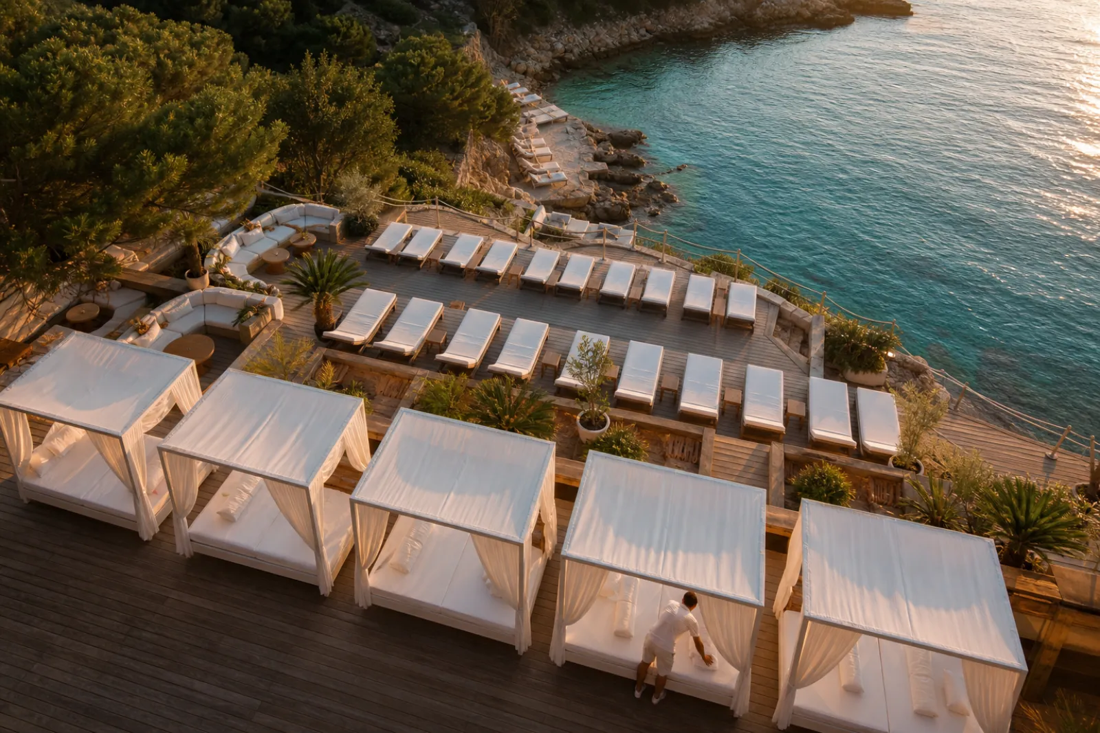 Aerial view of a beach club deck with rows of reserved daybeds at golden hour